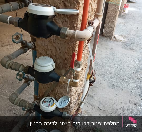 מד מים עם צינורות וברזים מותקנים על קיר